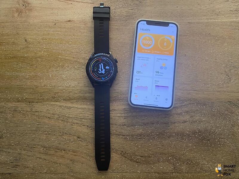 Man sieht die Huawei Watch GT 3 neben einem iPhone auf dem Tisch liegen.